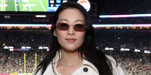 Arden Cho was seen wearing gold Miu Miu MU B50S 5AK20I rimless sunglasses with brown lenses at Super Bowl LX in San Francisco, February 2026