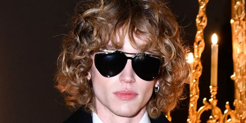 Creator Jordan Huxhold was seen wearing black and gold Saint Laurent Sun SL M137 Amelia 001 sunglasses at the Saint Laurent Menswear Fall/Winter 2025 fashion show during Paris Men's Fashion Week.