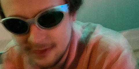 Actor Logan Miller was seen wearing grey silver Oakley Eye Jacket Redux OO9438 05 Prizm Polarised sunglasses in his Instagram post, August 2022.