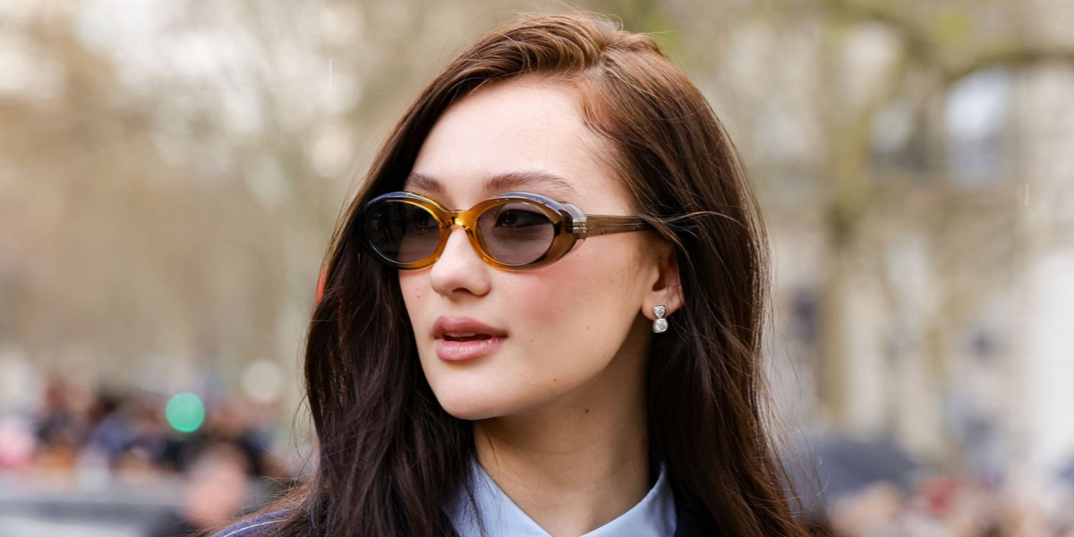 The Summer I Turned Pretty actress Lola Tung was seen wearing transparent yellow beige Miu Miu MU B09S 24M50Q Reverie oval sunglasses with grey lenses at the Miu Miu Fall/Winter 2026 fashion show during Paris Fashion Week.