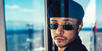 Colombian YouTuber Mario Andres Ruiz was seen wearing gold Prada PR B54S 5AK40K rectangular sunglasses with blue-green lenses in Las Vegas, shared through his Instagram post in November 2025.