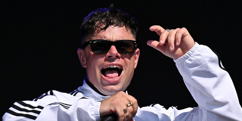 Irish rapper Moglai Bap or Kneecap was seen wearing black Ray-Ban New Wayfarer 2132 901/58 Polarised sunglasses onstage at the Glastonbury Festival 2025. Shop online now on Pretavoir