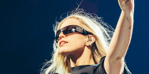 Renee Rapp was seen wearing black Balenciaga BB0359S 005 wraparound sunglasses with crystal-studded double B logo onstage during her performance in Berlin, March 2026.