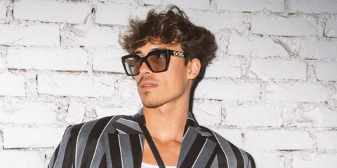 German content creator, actor, and model Tim Schaecker was seenwearing black and gold Versace 4418 GB1/87 sunglasses at the Versace Menswear Fall/Winter 2023 fashion show during Milan Men's Fashion Week