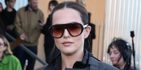 Zoey Deutch was seen wearing brown Prada PR C05S 27I70X sunglasses with burgundy to brown gradient lenses at the Prada Fall/Winter 2026 fashion show during Milan Fashion Week.